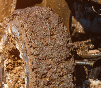 A close up of ATV tires in the mud on the right side. There is mud all over the tires and the ATV.